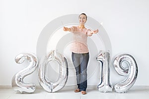 New 2019 Year is coming concept - Happy woman standing near silver colored numbers and sparklers indoors.