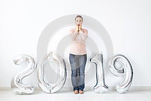 New 2019 Year is coming concept - Surprised young woman standing near silver colored numbers indoors.