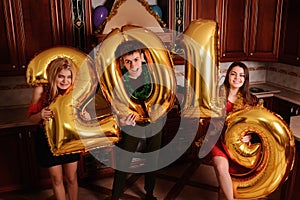 New 2019 Year is coming. Group of cheerful young people carrying gold colored numbers and have fun at the party