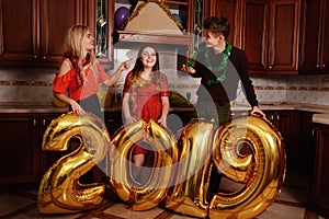 New 2019 Year is coming. Group of cheerful young people carrying gold colored numbers and have fun at the party