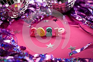 New 2021 year coming instead of 2020. Wooden numbers on a purple background among confetti and disco balls. New Year and Merry