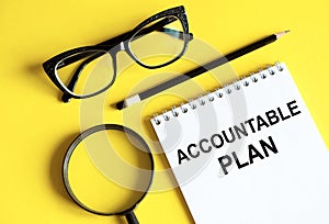 New ACCOUNTABLE PLAN text written on a notebook with glasses, magnifying glass and pencil