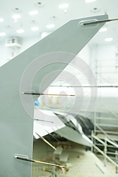 New aircraft component undergoes assembly process in high-tech workshop with bright overhead lights and advanced tools present