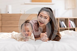 New asian mom Newborn baby laying on stomach developing neck control.tummy time for strengthen baby neck and shoulder muscles.Cute