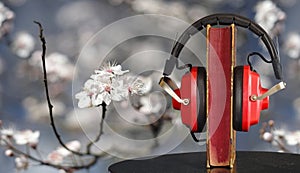 New audio book releases for spring and summer 2023 with book, vinatge headphone and cherry blossoms background.Spring Book fair,