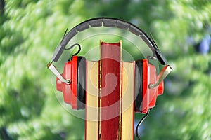 New audiobook releases for spring and summer holiday read and listening with row of books ang vintage headphone,blurred swirly