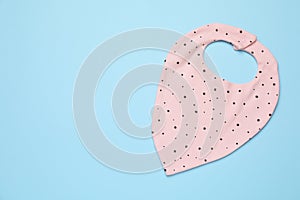 New baby bib on light blue background, top view. Space for text
