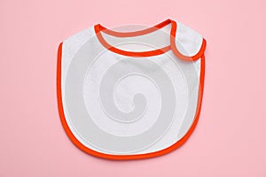 New baby bib on pink background, top view. First food