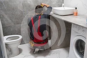 New Bathroom Interior Finishing. Caucasian Men in His 30s Assembling Modern Cabinets. Home Interior Remodeling Theme.