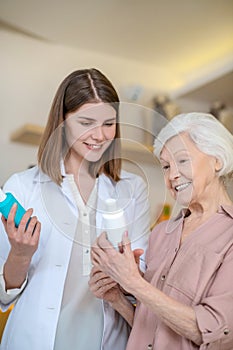 Young dark-haired cosmetologist demonstrating new cosmetic products to a female customer