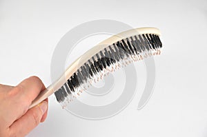 New beige oval hairbrush with bristles in a hand