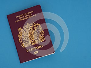 New Bergundy UK passport, no longer showing words `European Union`. On blue surface.