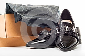 New black feminine beautiful patent leather shoes in a box isolated on white background