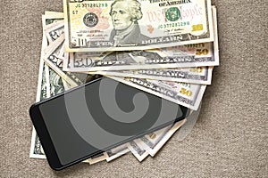 New black modern cellphone on money dollars banknotes background. Modern technology, communication and online trade using gadget