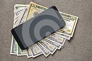 New black modern cellphone on money dollars banknotes background. Modern technology, communication and online trade using gadget