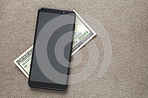 New black modern cellphone on money dollars banknotes background. Modern technology, communication and online trade using gadget