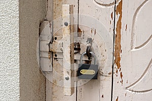 New black padlock on old white rusty door