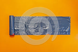 new black trash bag roll on the colorful surface, isolated, care the planet