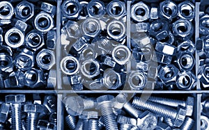 New bolts and nuts sorted in container shot closeup, background, mechanic work concept