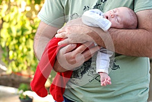 New born baby girl sleeping in her fathers arms