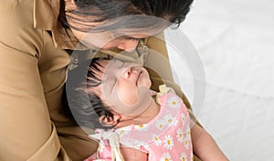 New born baby girl sleeping on mother arm on white bed at home