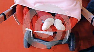 New born baby swinging her feet while sleeping in a stroller, top view