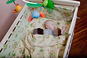 New born child in wooden co-sleeper crib. Infant sleeping in bedside bassinet. Safe co-sleeping in a bed side cot. Little boy taki