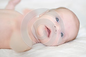 New born girl age two weeks is lying in bed and looking around with interest