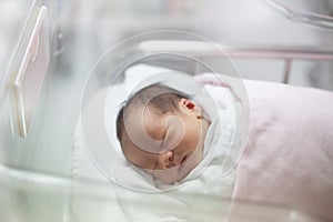 New born infant asleep in the blanket in delivery room photo