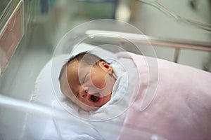 New born infant asleep in the blanket in delivery room