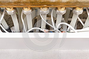 New brass manifold for underfloor heating with plastic pipes and connected electric cables for thermoelectric actuators.