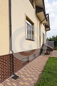 New brown copper gutter in house with white wall and new brick. Close up view on house problem areas for rain gutter.