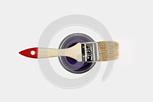 A new brush lies on the can with paint. Isolated on white background. View from above