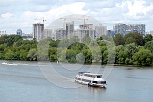 New building construction in new district after river with ship over sky with white clouds in summer day