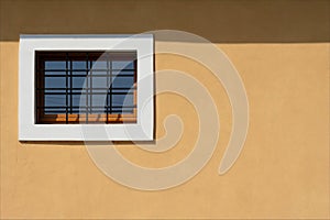 New building facade with yellow wall and barred window and with white marble frame.