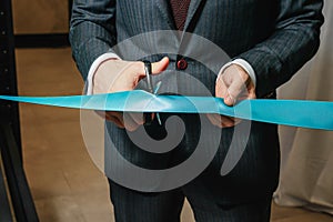 New business enterprise, opening, cutting a blue ribbon with scissors close-up