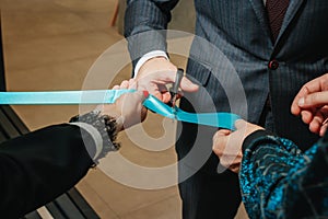 New business enterprise, opening, cutting a blue ribbon with scissors close-up