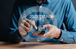 New business target start up in new years, Businessman using smartphone to input keyword of 2023 trends inside infographic