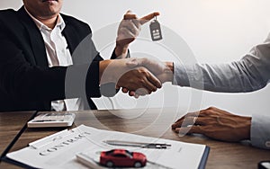 New car buyers and car salesmen are shaking hands to make agreements about car sales