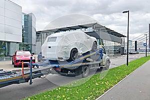 New cars covered with a protective cover material loaded on a truck