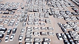 New cars covered in protective white sheets parked in a holding platform.