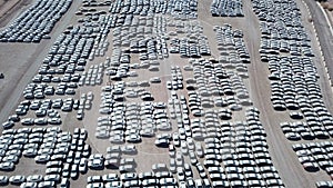 New cars covered in protective white sheets parked in a holding platform.