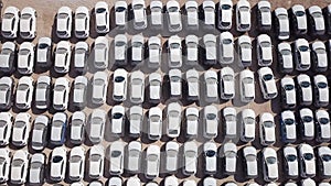 New cars covered in protective white sheets parked in a holding platform.