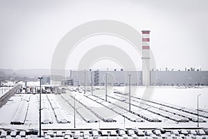 New cars covered with snow and parked in a distribution center on a cloudy day in the winter, a car factory