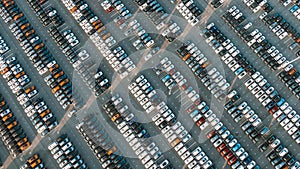 New cars stand in even rows in a giant park at a car factory, aerial view