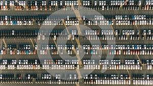 New cars stand in rows at a car factory site, aerial view