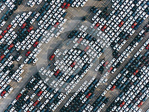 New cars are standing in straight diagonal rows in the parking lot, aerial view