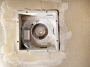 New ceiling fan duct being installed in bathroom ceiling with sheetrock being repaired