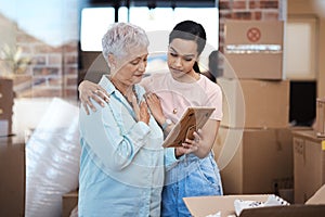 A new chapter comes with a few adjustments. a senior woman looking at a photograph with her daughter while packing boxes