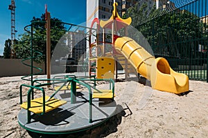 New children`s playground with a yellow slide and a swing in the summer on a sunny day